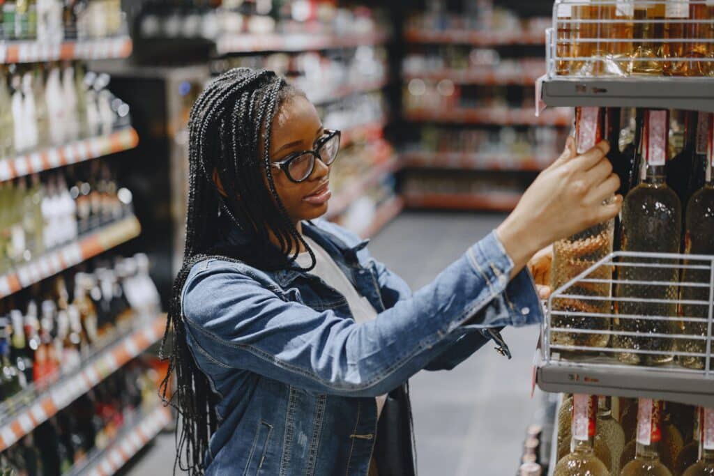 a shopper looks at a bottle of wine in a convenience store