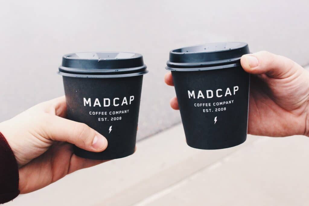 an example of small business branding showing a paper coffee cup from Madcap coffee company