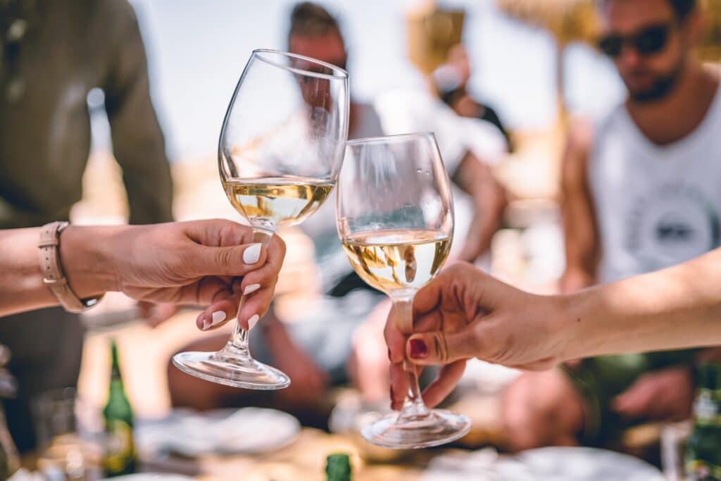 two people cheers glasses of white wine at a wine brand tasting