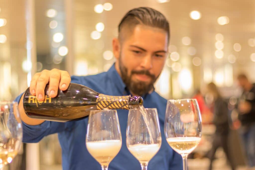 a retail employee pours champagne into three glasses at a wine tasting