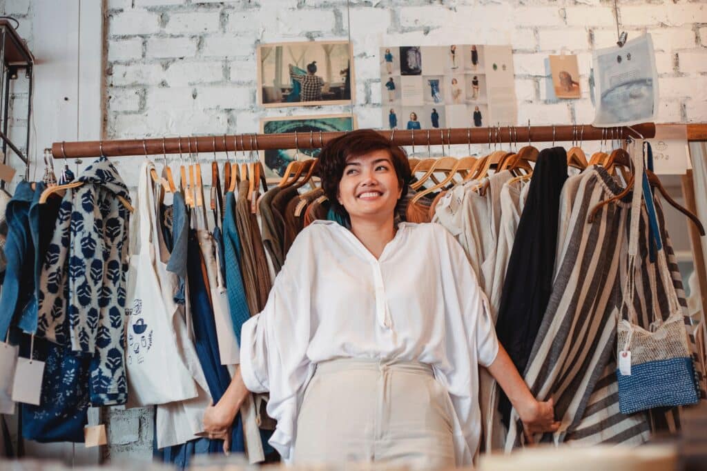 a retail shop owner stands in front of a rack of clothing