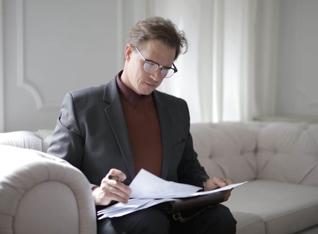 a retail business owner looks over paperwork while seated on a couch