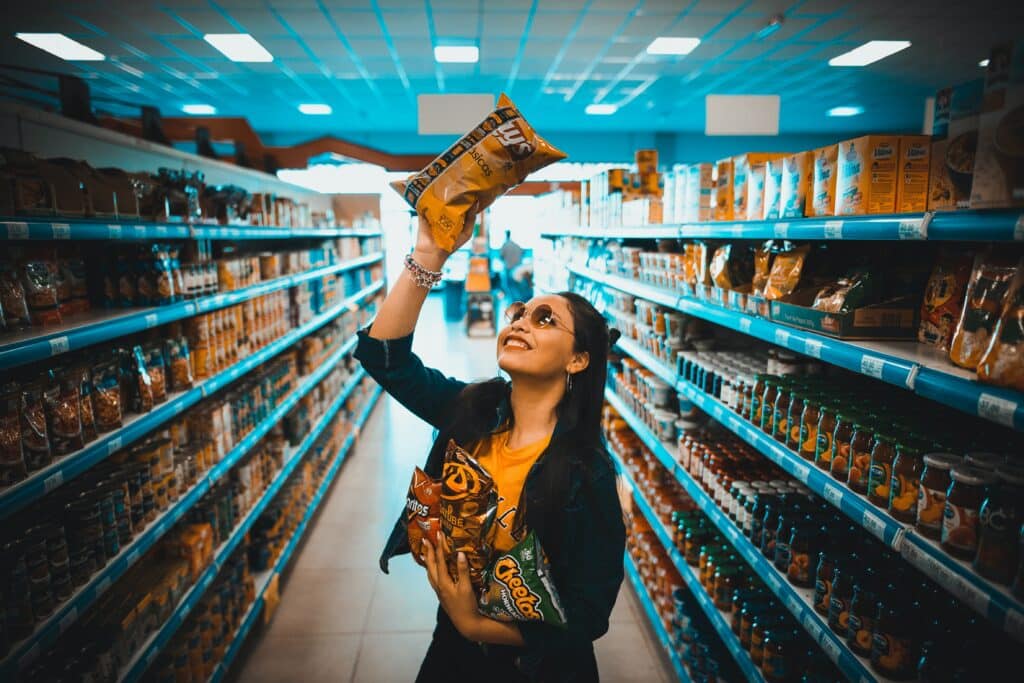 a grocery store shopper smiles as they hold a bag of chips