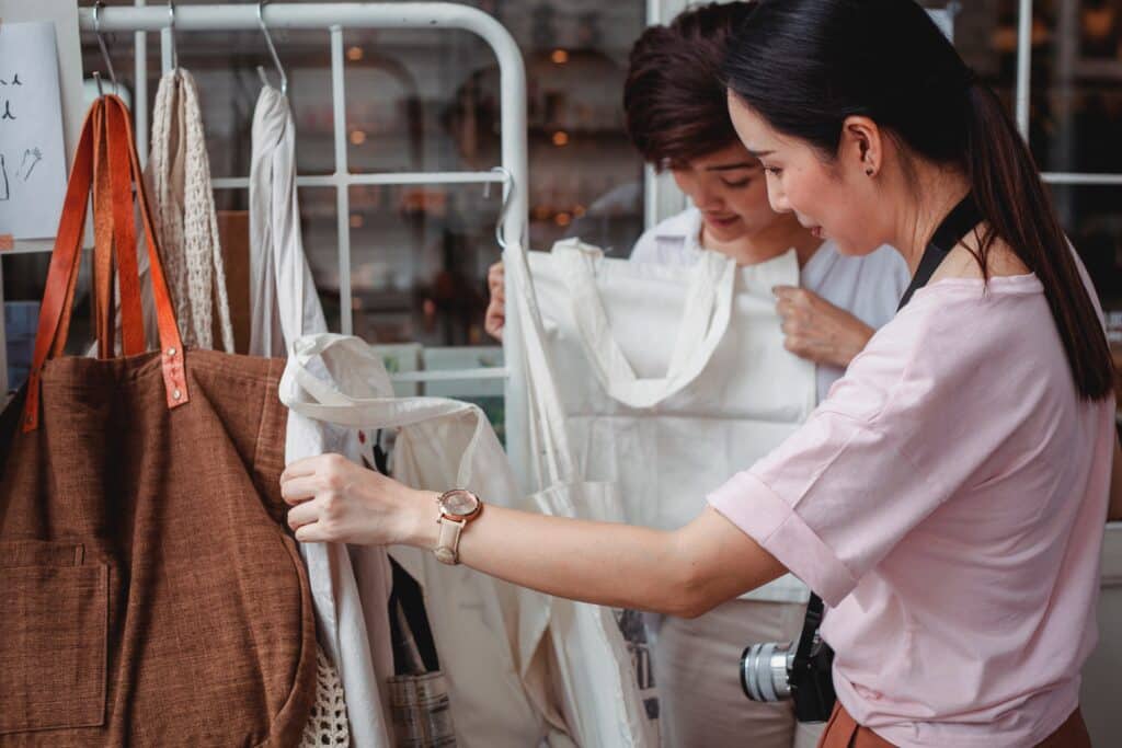 retail customers smile as they look at canvas bags in a shop