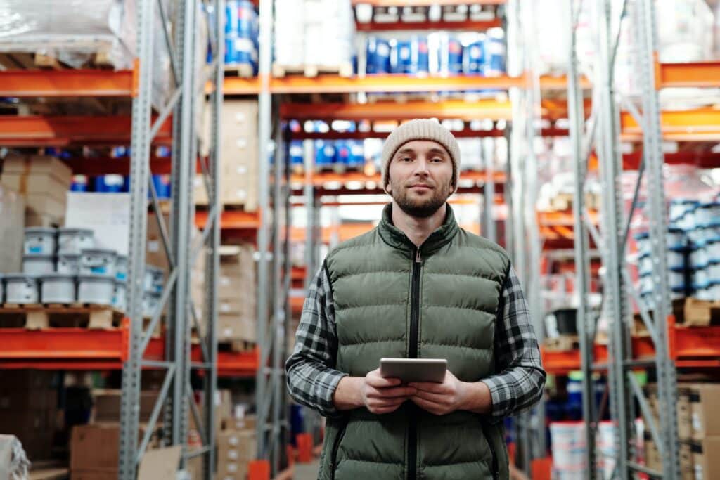 a retail employee stands in a warehouse holding a tablet for RFID data collection  and inventory management