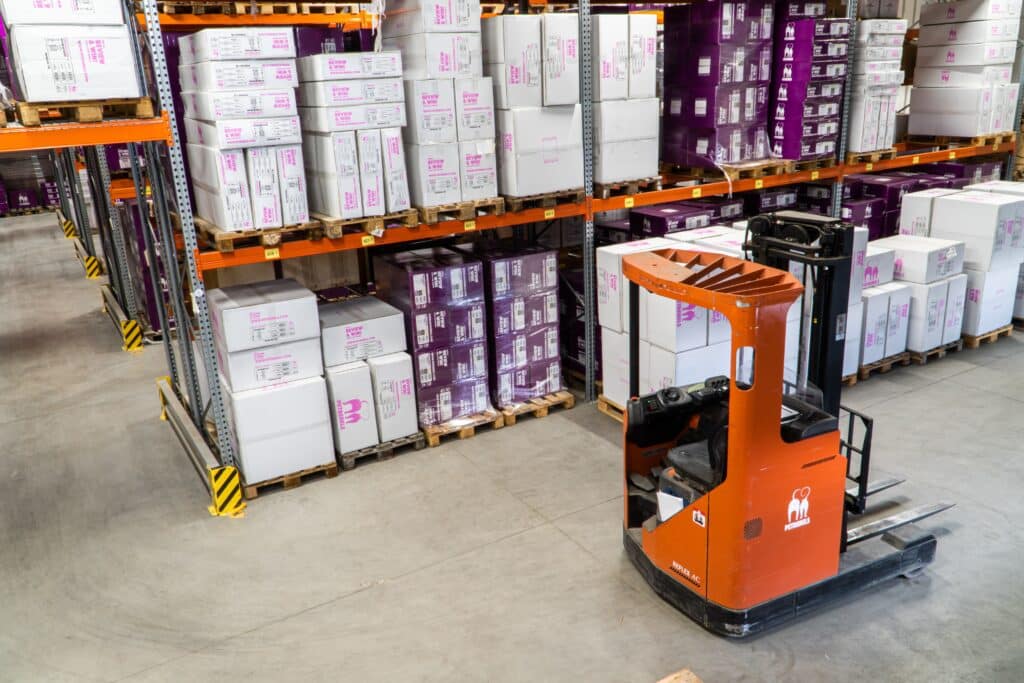 a forklift and shelves of goods in a warehouse of a distributor