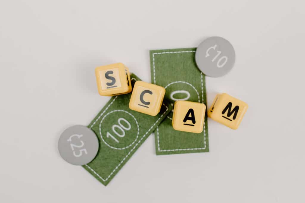 fake money sits around letter blocks that read "scam"