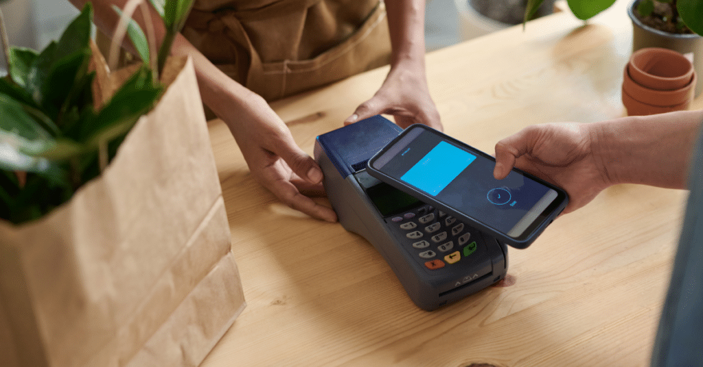 Cashier ringing up sales in a stores with a credit card machine that accepts contactless payments from a smartphone