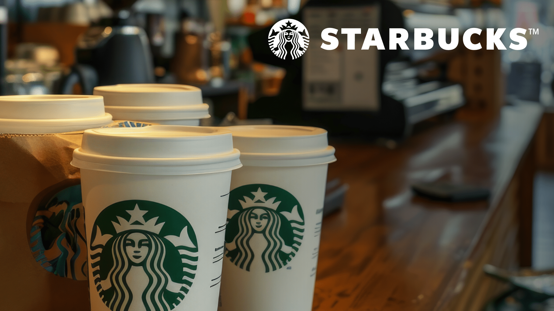 Starbucks coffee shop counter with several cups of coffee ready to take to go and a Starbucks POS system in the background