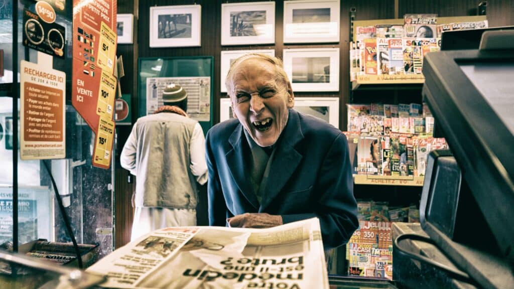 Older man smiles as he checks out at a small retail store