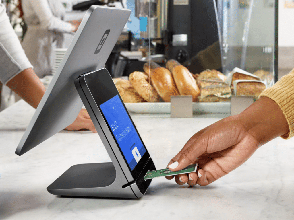 Picture showing a  cashier swiping a card through a Square POS hardware 