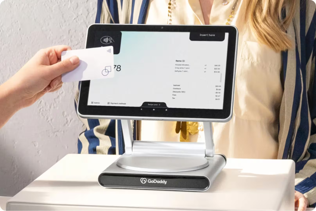 go daddy smart terminal pro on a cash box with someone scanning a credit card